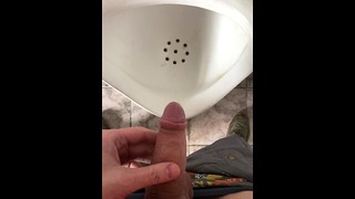 Peeing in a urinal in a men’s public restroom